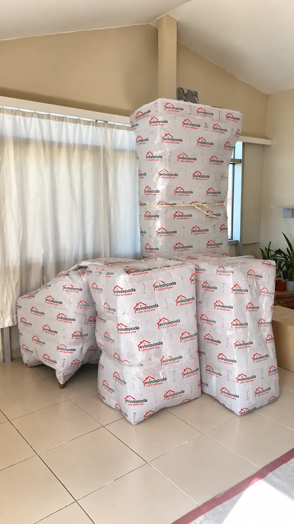 Logolu sargı malzemesiyle paketlenmiş koltuk ve mobilyalar, evde pencere önünde